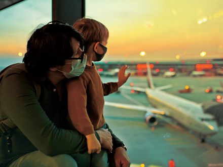 Masked man and boy looking through airport window