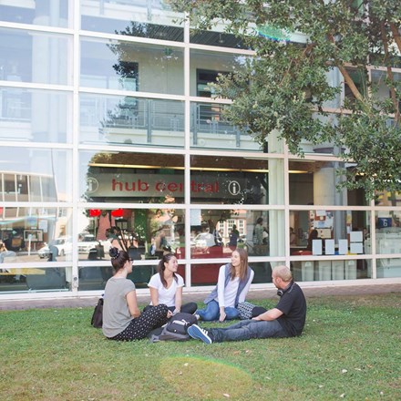 Students sitting on green grass on campus setting