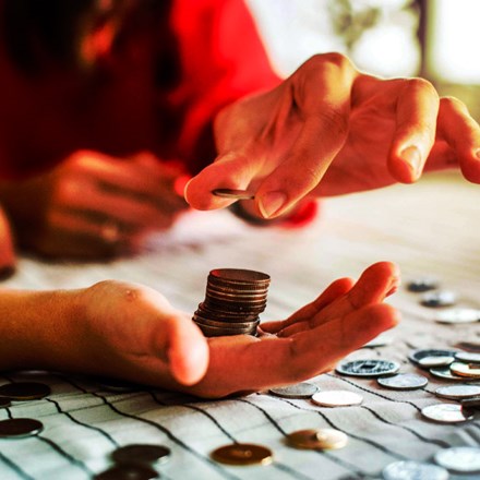 Woman's hands counting coins on a table.