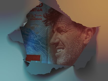 Part of New Zealand $5 bill peeking through a torn hole in paper.