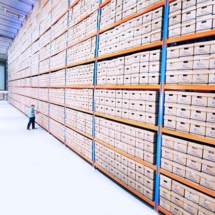 Man in a warehouse in front of a wall of boxes.