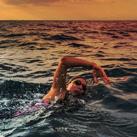 Female open water swimmer swimming forward crawl in sea.