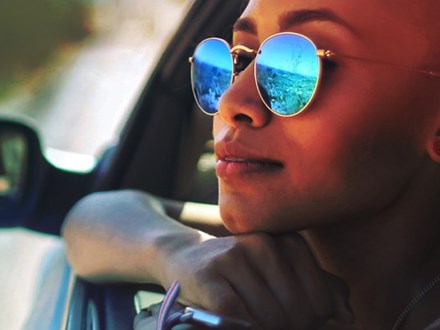 Woman with sunglasses leaning out a car window.