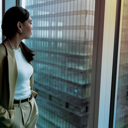 Woman standing at window of skyscraper