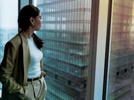 Woman standing at window of skyscraper