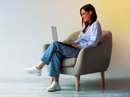 Content woman sitting in grey chair working on laptop